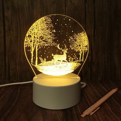 an illuminated night light with a deer in the woods on it's side, sitting on a table