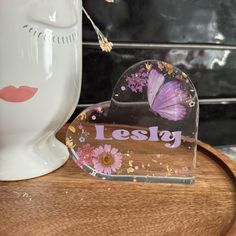 a heart shaped mirror sitting on top of a wooden table next to a white vase