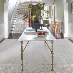 a living room filled with furniture and a white table in front of a stair case