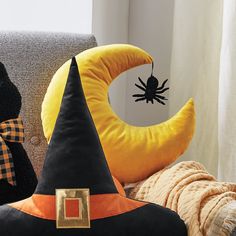 two halloween decorations sitting on top of a couch next to a black cat and yellow moon