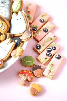 a plate full of decorated cookies on top of a pink table with mushrooms and other decorations