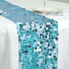 the table runner is decorated with blue sequins and has a wine glass on it