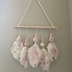 three pink and white tassels hanging from a wooden frame on the wall next to a gray wall