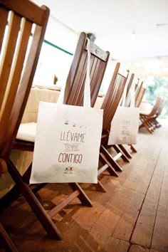 a row of wooden chairs sitting next to each other on top of a hard wood floor