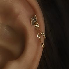 a close up of a person's ear wearing gold jewelry