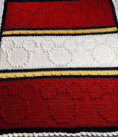 a crocheted blanket with red, white and yellow stripes on it's edges