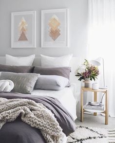 a bedroom with two pictures above the bed and pillows on the side table next to it