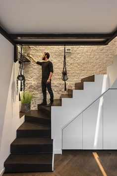 a man is walking up the stairs in his home with hanging objects on the wall