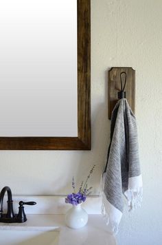 a white sink sitting under a mirror next to a wooden frame