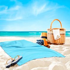 a beach towel, sunglasses and hat on the sand