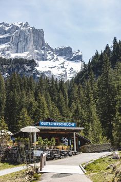 an outdoor restaurant with mountains in the background and trees on either side that have snow capped peaks