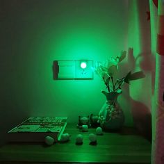 a green light shines on a table next to a vase with flowers