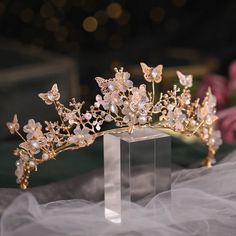 a gold tiara with white flowers and butterflies on the headpiece is sitting on a table