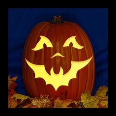 a carved pumpkin with bats on it and leaves around the whole pumpkin, in front of a blue background