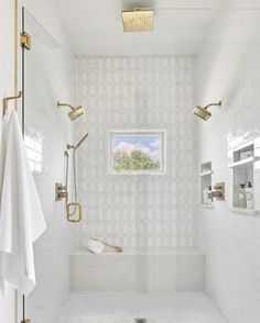 a white tiled bathroom with gold fixtures and shower head mounted to the side of the bathtub