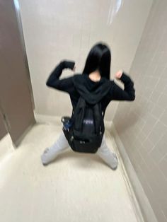 a woman sitting on the floor in a bathroom with her back to the camera and arms behind her head