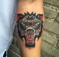 a man with a tattoo on his arm has a wolf's head in the center