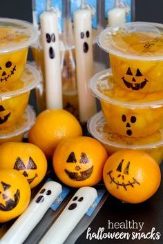 oranges with faces drawn on them sitting in front of candles and halloween themed decorations