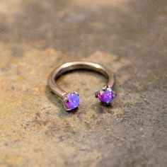 an opal stone ring sits on the ground