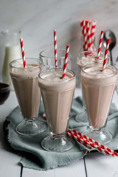 three glasses filled with milkshakes sitting on top of a table