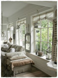 a living room filled with lots of furniture next to a window covered in hanging birdcages