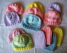 six knitted hats laid out on a table