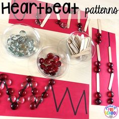 two bowls filled with candies on top of a table next to matches and hearts