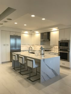 a large kitchen with marble counter tops and stainless steel appliances