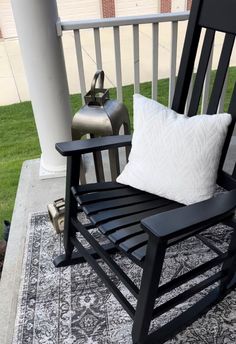 a black rocking chair sitting on top of a rug next to a white and black pillow