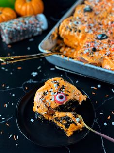 a black plate topped with cake covered in sprinkles and an eyeball