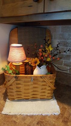 a basket filled with flowers on top of a counter next to a lamp and rug