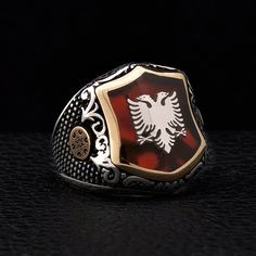 "Silver Albanian Eagle signet on the red pearl. There is illyrian shield symbol at the sides of the ring. Illyrians are considered to be the ancestors of the Albanian nation. This ring has Red Pearl Stone under the Albanian Double Head Eagle. I am designing a logo or symbol for you on the stone's empty area by use enamel work. Items has 1 year guaranty for the production mistakes. Stone: Red Pearl Material: Sterling Silver 925k and Bronze Plated: Rodium Plated Weight: 16.00gr Please make sure yo Heirloom Red Signet Ring With Polished Finish, Formal Red Engraved Ring With Polished Finish, Red Symbolic Sterling Silver Ring, Red Engraved Signet Ring For Formal Occasion, Luxury Red Signet Ring, Formal Red Engraved Signet Ring, Collectible Red Rings With Polished Finish, Symbolic Red Jewelry For Anniversary, Symbolic Red Gemstone Jewelry