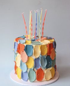 a multicolored birthday cake with candles on it