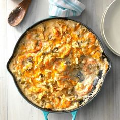 a casserole dish is sitting on a table next to some plates and utensils