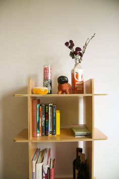 a bookshelf with several different types of books on it and a vase filled with flowers