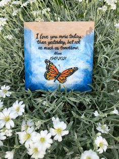 a card with a butterfly on it sitting in the middle of some white daisies