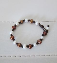 This bracelet has 7mm round brown & white freshwater pearls hand knotted on dark brown leather.   Clasp is another pearl with loop.   Looks great worn on it's own or stacked with other bracelets from my shop for a truly Boho look! Brown Leather Bracelet With Round Beads, Brown Hand-strung Leather Bracelet Gift, Hand-strung Brown Leather Bracelet Gift, Peacock Pearl, Biwa Pearls, White Bracelet, Black Leather Bracelet, White Bracelets, Freshwater Pearl Bracelet