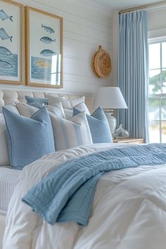 a bed with blue and white pillows in a bedroom next to two pictures on the wall