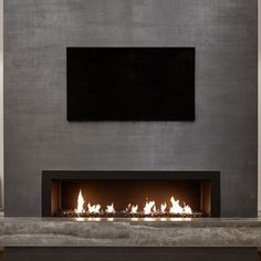 a modern fireplace with a flat screen tv above it and lit flames in the middle