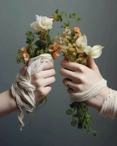 two hands holding flowers tied to each other