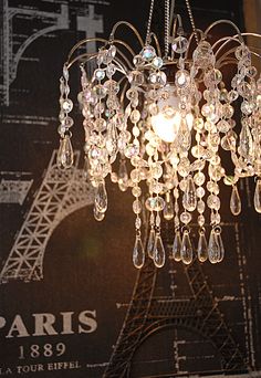 a chandelier hanging in front of the eiffel tower with crystal drops