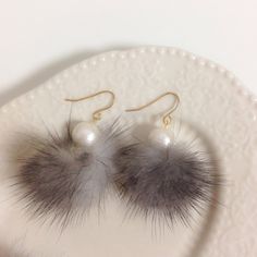 a pair of fur and pearl earrings on a plate