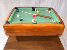 a cake made to look like a pool table with cues and balls on it,