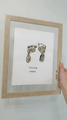 a person holding up a framed photo with two baby feet