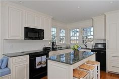 a kitchen with white cabinets and black appliances