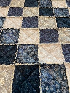 a blue and white quilt on top of a wooden tablecloth covered in black and tan fabric