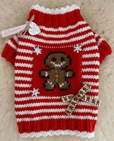 a red and white striped sweater with a teddy bear on it, next to a small bow