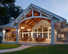 a large house with a covered patio and dining area in the front yard at dusk