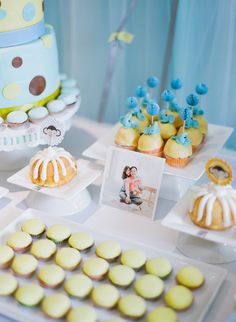 a table topped with lots of cupcakes next to a cake and other dessert items