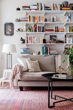 a living room filled with furniture and lots of books on the shelves above it is a coffee table